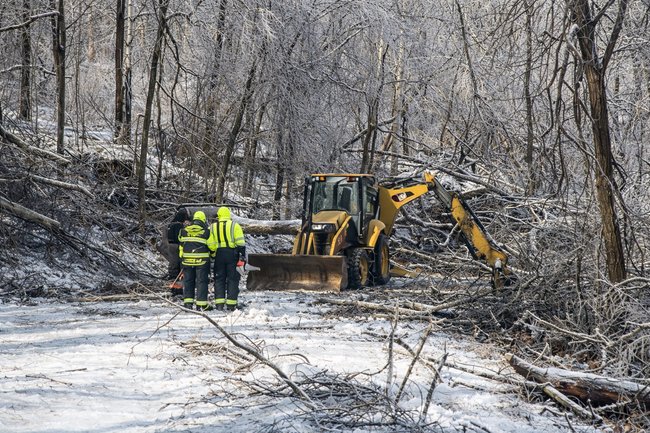 Photo showing linemen clearing a road after a bad storm related to self-sufficient living.