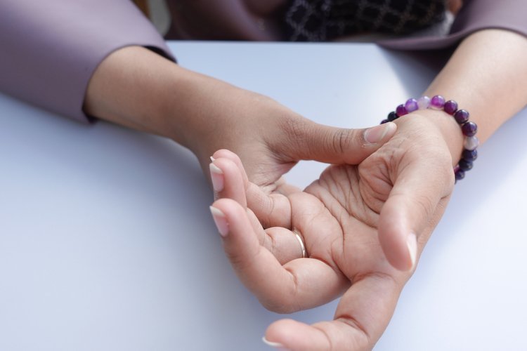 Woman rubbing her hand and fingers to relieve tingling or numbness caused by circulation or nerve pressure