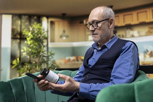 Senior man reviewing medication while sitting at home highlighting potential side effects