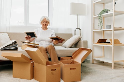 Older woman organizing boxes while downsizing to declutter sentimental items