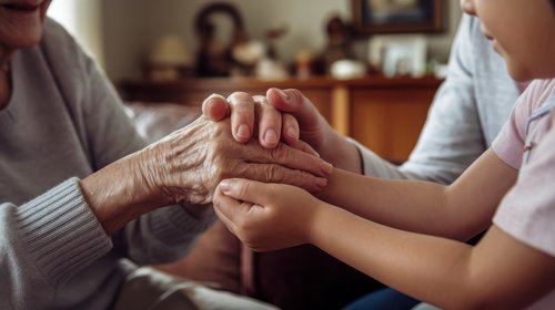 Child holding elderly grandparent’s hands during the emotional family transition of helping parents downsize