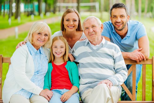 Multi-generational family including grandparents, parents, and child sitting together outdoors when moving after 50